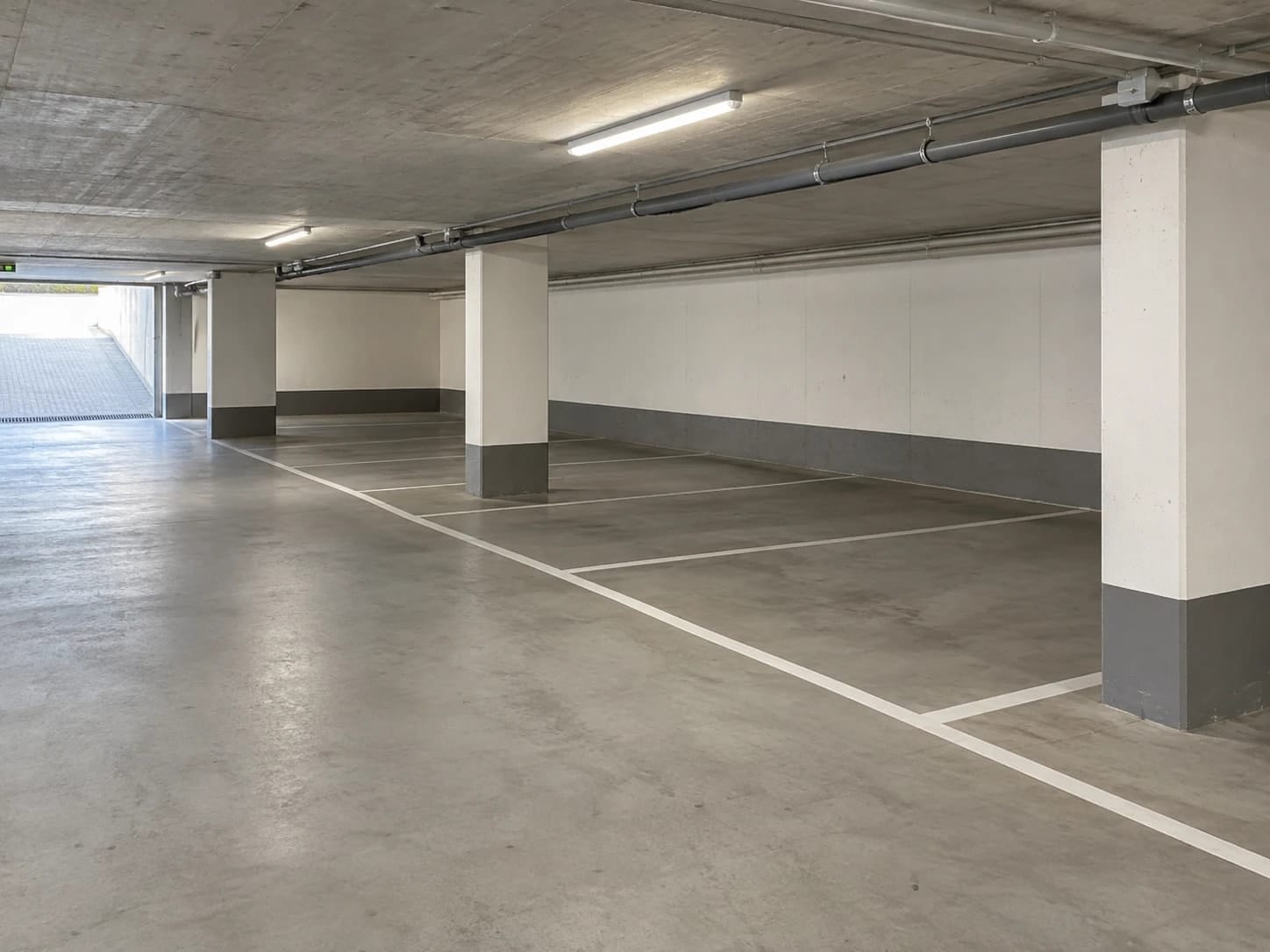 Tiefgarage mit Betonboden, weißen Stellplatzmarkierungen und hellen Stützen – KI-generiertes Symbolbild