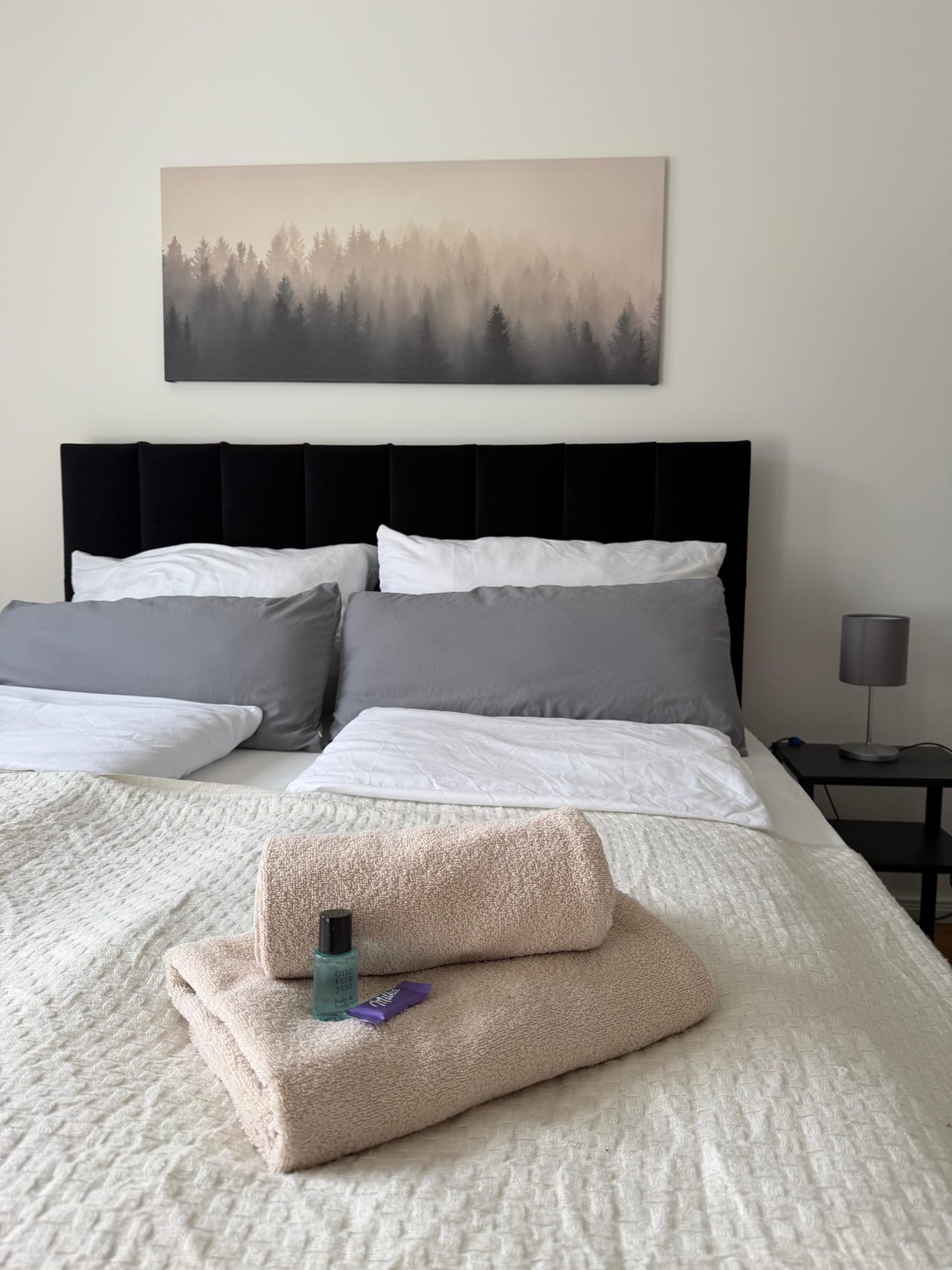 Zusammengelegte Handtücher und kleine Aufmerksamkeiten auf einem gemachten Bett