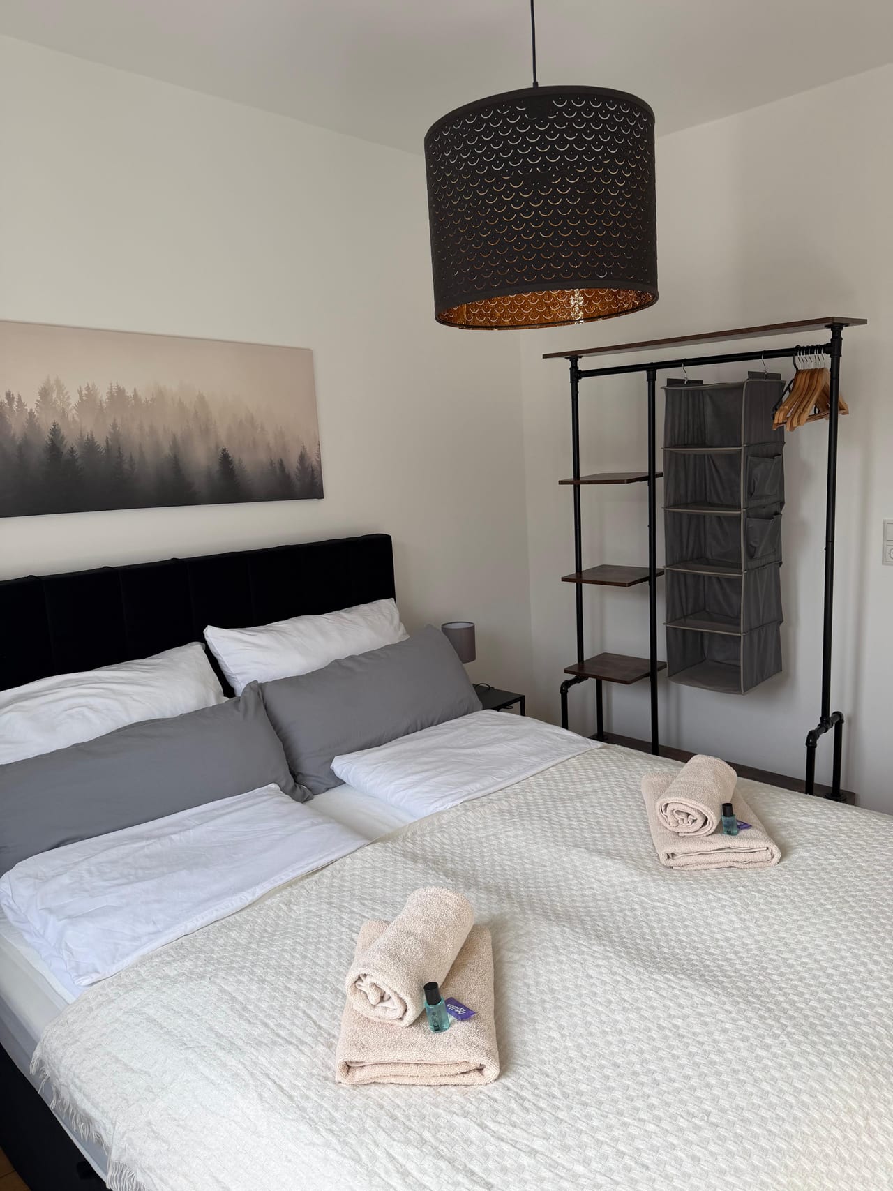 Gemachtes Doppelbett mit Handtüchern neben einem offenen Kleiderständer